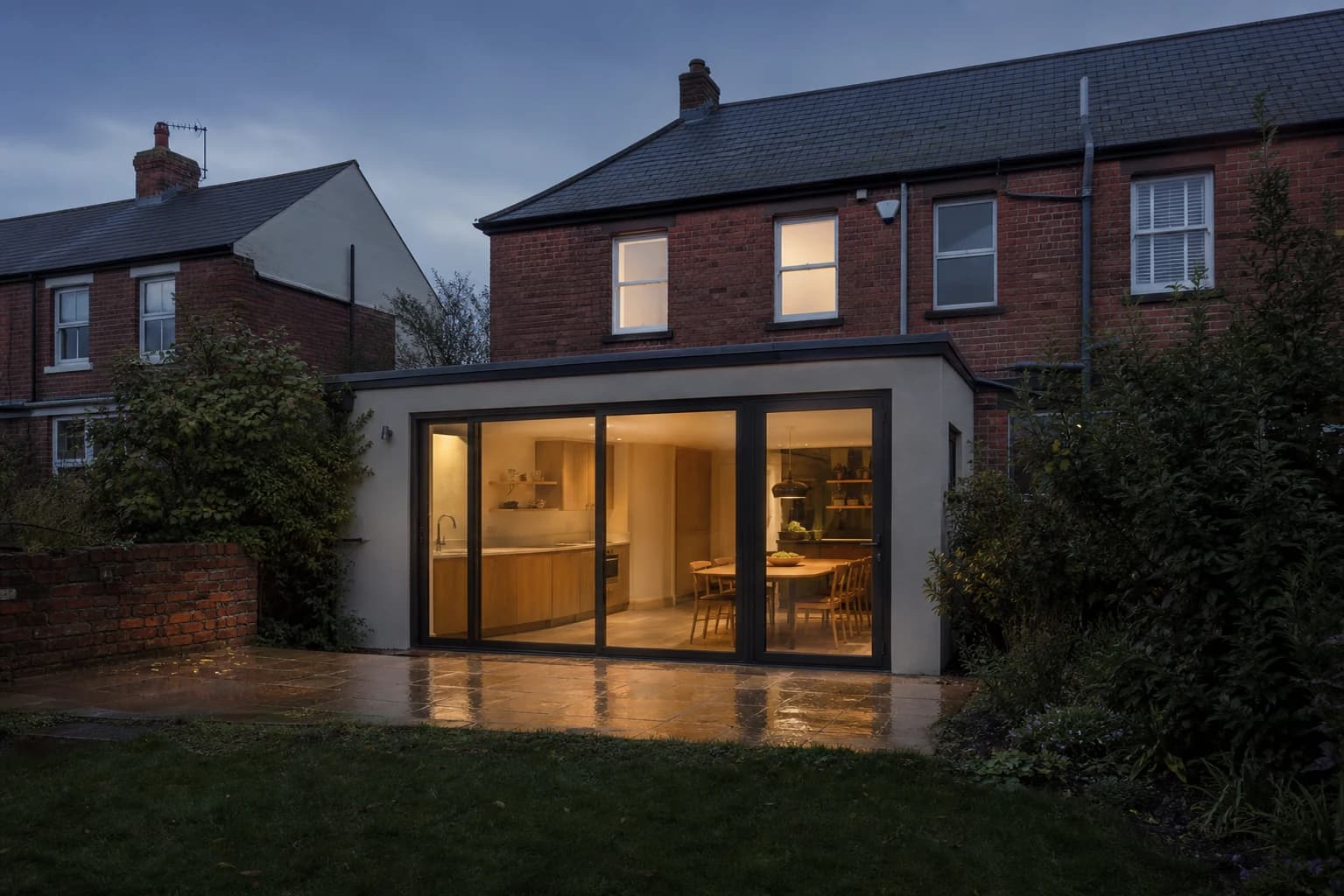 Design visualisation of a modest South Wales home with a glazed rear extension at dusk